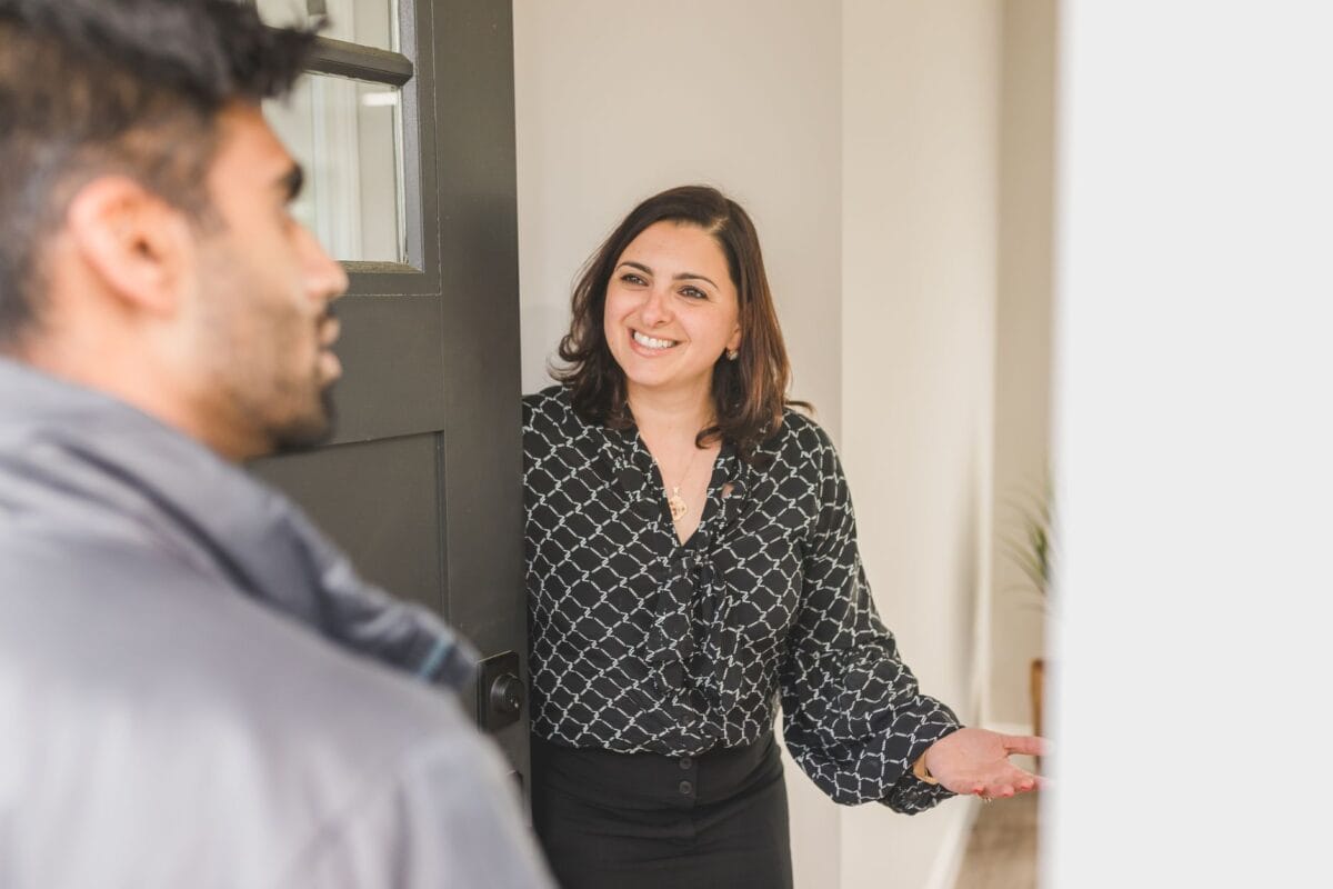 Family Cosmetic Dentistry Worcester: The Power of a Great First Impression - Friendly Dental of Worcester Woman smiling and talking with a colleague at an office doorway, gesturing with her hands