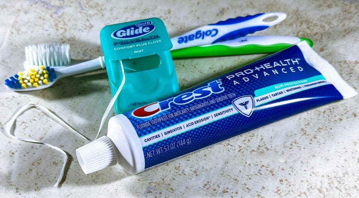 Family Cosmetic Dentistry Worcester: Health Meets Beauty - Friendly Dental of Worcester Tube of Crest Pro-Health Advanced toothpaste with mint-flavored floss container and two toothbrushes on a marble counter (informative).